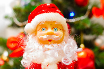 Toy Santa Claus, on the background of the New Year tree, and on the background of the New Year star on the Christmas tree. Toy Santa in close-up. Christmas decoration. Celebration.