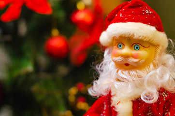 Toy Santa Claus, on the background of the New Year tree, and on the background of the New Year star on the Christmas tree. Toy Santa in close-up. Christmas decoration. Celebration.