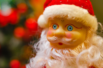 Toy Santa Claus, on the background of the New Year tree, and on the background of the New Year star on the Christmas tree. Toy Santa in close-up. Christmas decoration. Celebration.