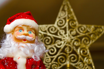 Toy Santa Claus, on the background of the New Year tree, and on the background of the New Year star on the Christmas tree. Toy Santa in close-up. Christmas decoration. Celebration.