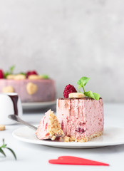 Sliced no bake raspberry cheesecake (cream mousse dessert) decorated with chocolate glaze, raspberries, heart shape cookies and mint. Valentine’s day concept. Selective focus.