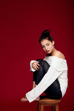 Romantic white girl sits on a chair nna red background.