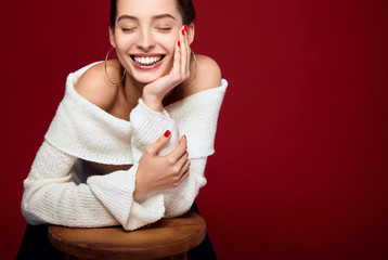 Portrait of caucasian female model standing and smiling against red background.