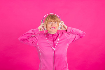 adult or senior woman with headphones listening to music in color background