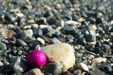 Christmas ball among beach stones