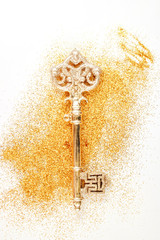 Golden key with sparkles on a background with glitter top view.