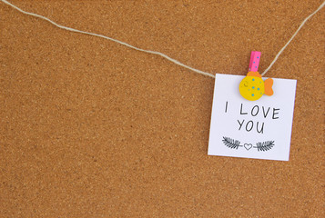 Lettering I love you with leaf pattern on white paper pinned with yellow fish mandala on cork board