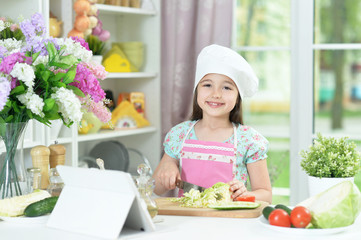 Portrait of cute girl preparing delicious fresh salad in kitchen