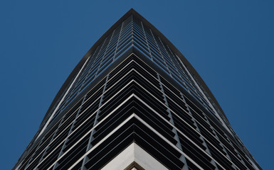 Fototapeta na wymiar View of the skyscraper from below against a blue sky. Close-up