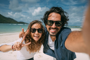 A pair of lovers take a selfie on a tropical beach.