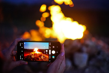 Girl shooting a photo to the fire with smartphone