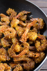 Breaded shrimps breaded in a large black pan, closeup vertical. The food is delicious Italian cuisine, Mediterranean recipe. Headless langoustine fried shrimp appetizer