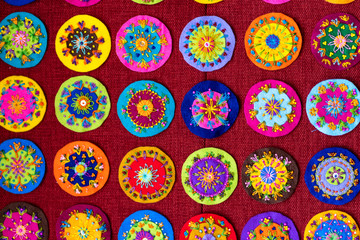 Small round embroidery, full of colors, shown on a red background