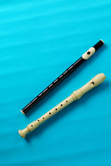 Two block flutes: black and soprano-white.Isolated, on blue background, vertical arrangement, copy space. Musical wind instrument.