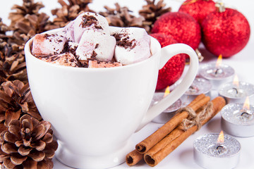 Cup of hot chocolate with marshmallows, and some cinnamon sticks, cones, christmas balls and candles	