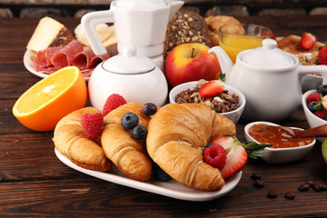 Breakfast served with coffee, orange juice, croissants, cereals and fruits. Balanced diet. Continental breakfast with granola and fruits