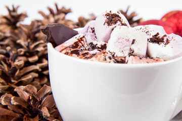 Cup of hot chocolate with marshmallows, and some cinnamon sticks, cones, christmas balls and candles	