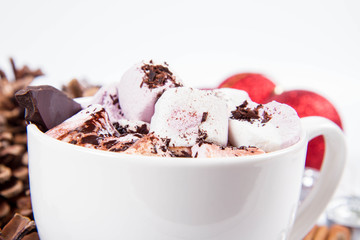 Cup of hot chocolate with marshmallows, and some cinnamon sticks, cones, christmas balls and candles	