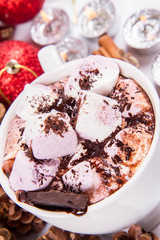 Cup of hot chocolate with marshmallows, and some cinnamon sticks, cones, christmas balls and candles	