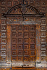 Old wooden textured front door to Italian, European house. Facade of antique home in Italy, entrance city door in Europe.