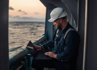 Marine chief officer or captain on deck of vessel or ship watching laptop. Internet and home...