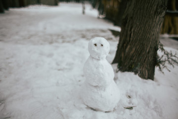 Funny snowman in winter Park. Child playing with snow. Kid sculpts big snowman. Children wintertime outdoor activity time concept.