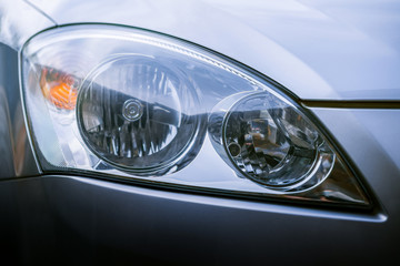 Headlights of the silver car close up with yellow turn signal. Clean glass after washing and wiping. The front of the car. Close-up exterior of the car xenon lamp.