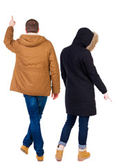 Back view of couple couple in winter jackets pointing.