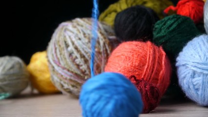 Multi-colored Balls Of Wool Thread For Knitting On The Black Background. Closeup. Unwinds A  Ball Of Blue Yarn.