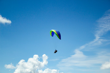 Paraglider in the blue sky. The sportsman flying on a paraglider.