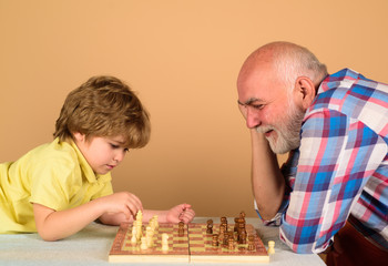 Checkmate. Games and activities for children. Grandfather and grandson playing chess. Child boy playing chess with grandfather. Little boy think or plan chess game. Little boy learning to play chess.