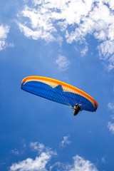Paraglider in the blue sky. The sportsman flying on a paraglider.