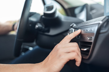 Transportation. Young man traveling by electric car sitting inside driving pressing button on...