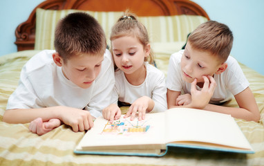 Three children are looking into a book only