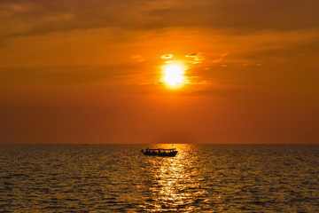 Lonely boat on a wide sea during beautiful orange sunset in Asia