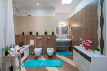 Brown and beige tile. Interior of bathroom in private house. Toilet and bath.