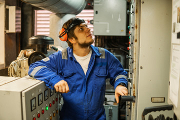 Marine engineer inspecting ship's engine or generators in engine control room ECR. Seamen's work.