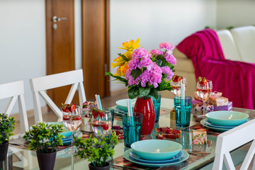 Close-up of laid table in modern studio apartment. Vase with flowers.
