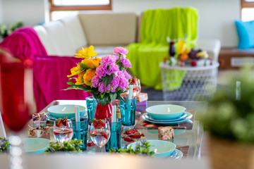 Close-up of laid table in modern studio apartment. Vase with flowers.