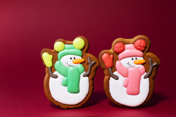 gingerbread cookie of cute snowman on red background. Traditional Christmas food. Christmas and New Year holiday concept.