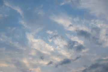 Thin white clouds against a blue sky move in front of a slowly rolling storm front