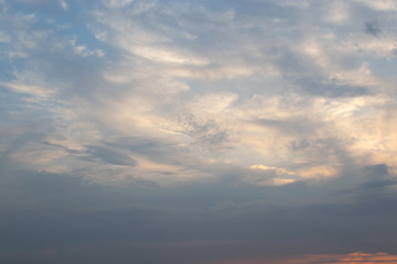 Thin white clouds against a blue sky move in front of a slowly rolling storm front