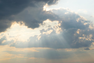 The sun's rays break through rare gaps among the dark thunderclouds hiding the sky