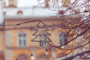 New Year and Christmas background. Christmas street decorations in snowfall. Garland on a background of tree branches and city architecture