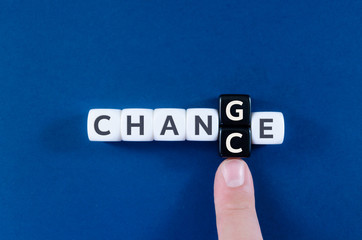 Index finger of a businessman changing the letters G and C to transform a Change sign into Chance spelled on  white and black cubes.