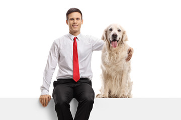 Formal young man hugging a labrador retriever dog seated on a panel
