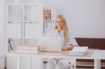 Portrait of smiling receptionist using laptop computer and headset at office desk