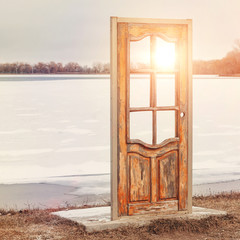 Abstract composition of a free-standing door in nature against the backdrop of a frozen lake in winter. The door to another world.