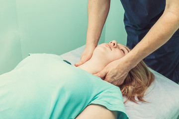 chiropractor massaging neck of patient that lying on massage table in hospital