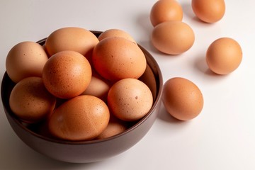 Brown eggs in a bowl on white background 